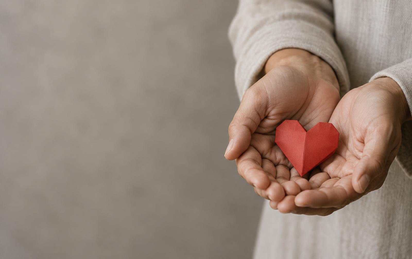 Hands holding a red paper heart for the Humanity Without Limits campaign